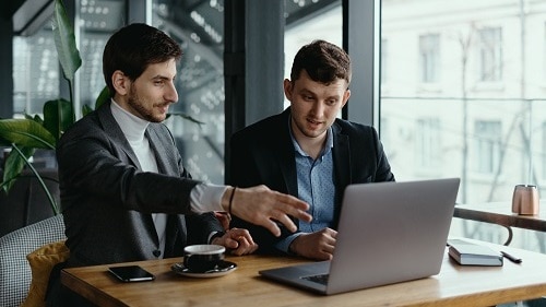 two-businessmen-pointing-laptop-screen-while-discussing