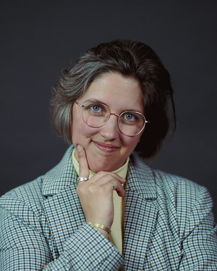 Mature businesswoman with glasses, hand to chin, thinking about selling her business